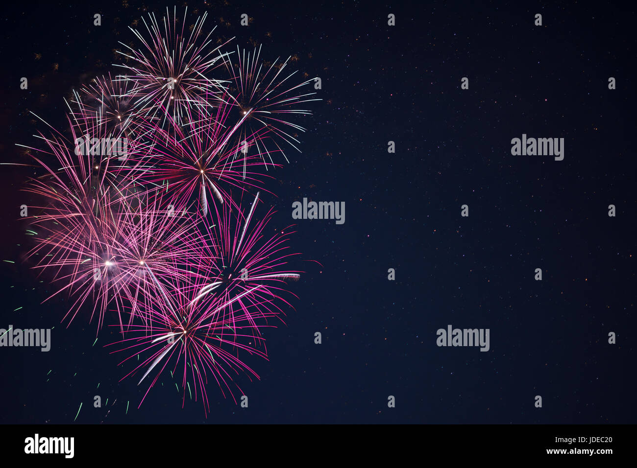 Bella maroon rosa rossa celebrazione fuochi d'artificio ubicata sulla sinistra oltre il cielo notturno, copia dello spazio. Giorno di indipendenza, 4 luglio, le vacanze di Capodanno Saluto Foto Stock