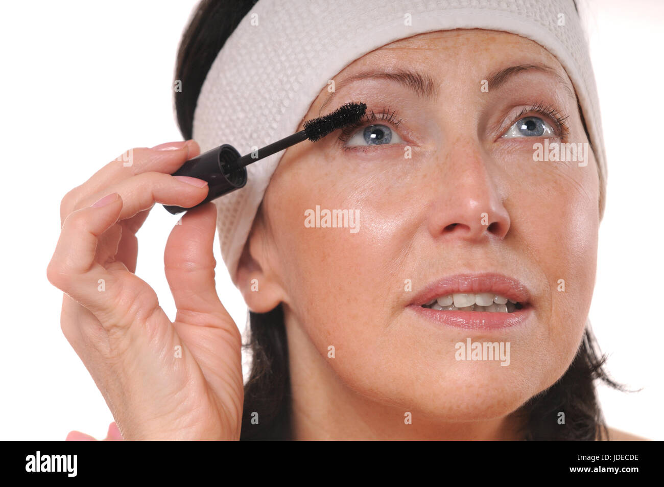 Closeup ritratto di donna matura applicazione di mascara sulle ciglia. Il 50-anno-vecchia donna mettere il mascara nella parte anteriore dello specchio Foto Stock