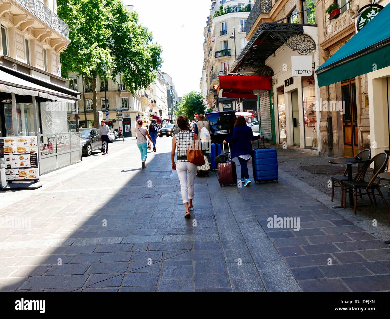 Giovane a piedi, tirando due valigie grandi ciascuno sulla giornata di caldo a Parigi, Francia Foto Stock