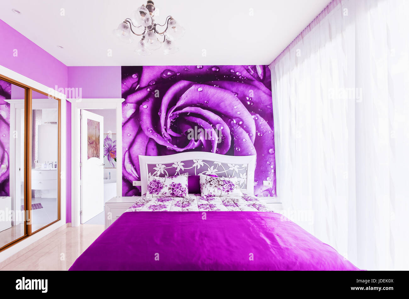 Interno della camera da letto accogliente in luminosi toni di viola. Grande armadio con specchi. Parete di carte su una parete. Foto Stock