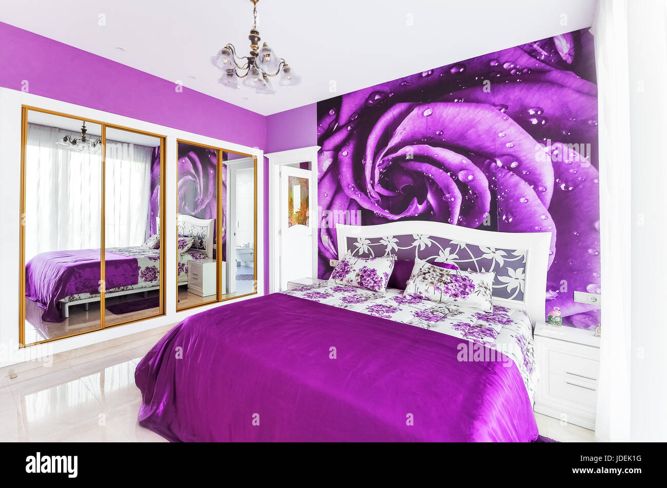 Interno della camera da letto accogliente in luminosi toni di viola. Grande armadio con specchi. Parete di carte su una parete. Foto Stock
