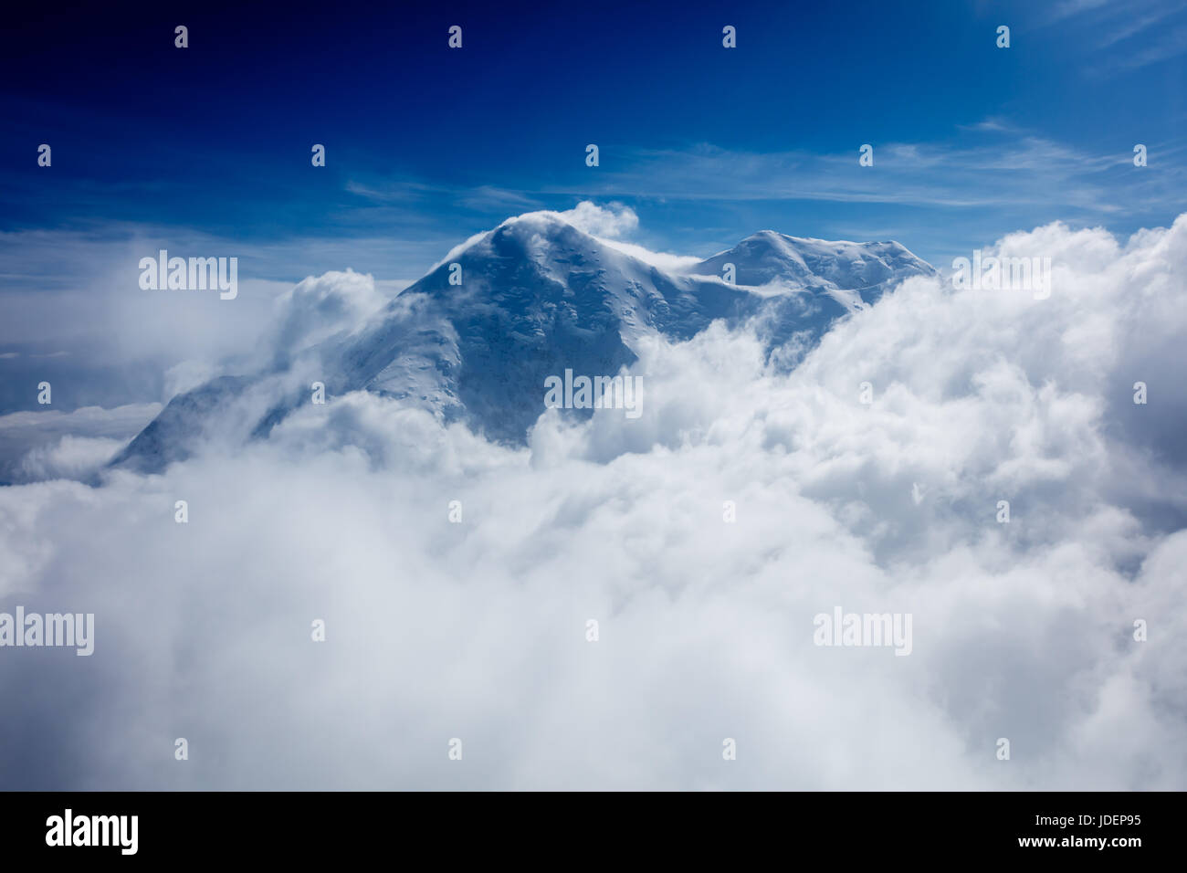 Vista aerea della top di Snow capped peak avvolte in nuvole sotto Foto Stock