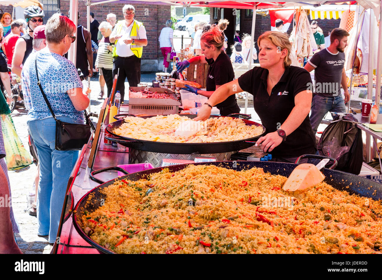 Evento francese, Le Weekend, alla cittadina inglese, sandwich. Donna raccogliendo porzione di paella da enormi cauldrons cottura a tented cibo all'aperto in stallo. Foto Stock