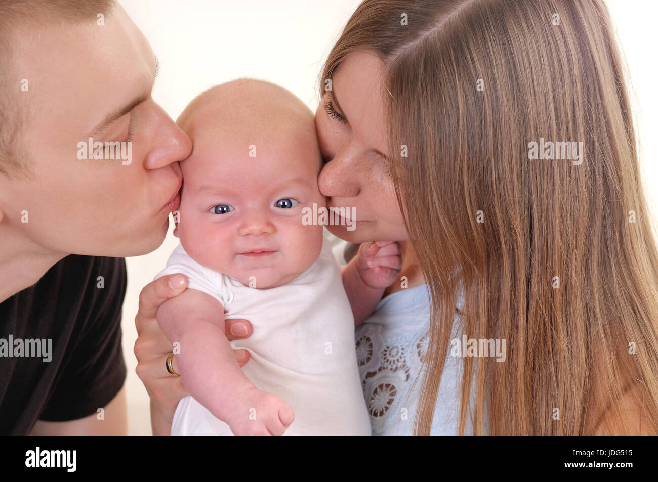 Closeup Ritratto di giovane e bella famiglia con il neonato. I giovani genitori entrambi baciare il loro dolce bambino. Felice genitorialità Foto Stock