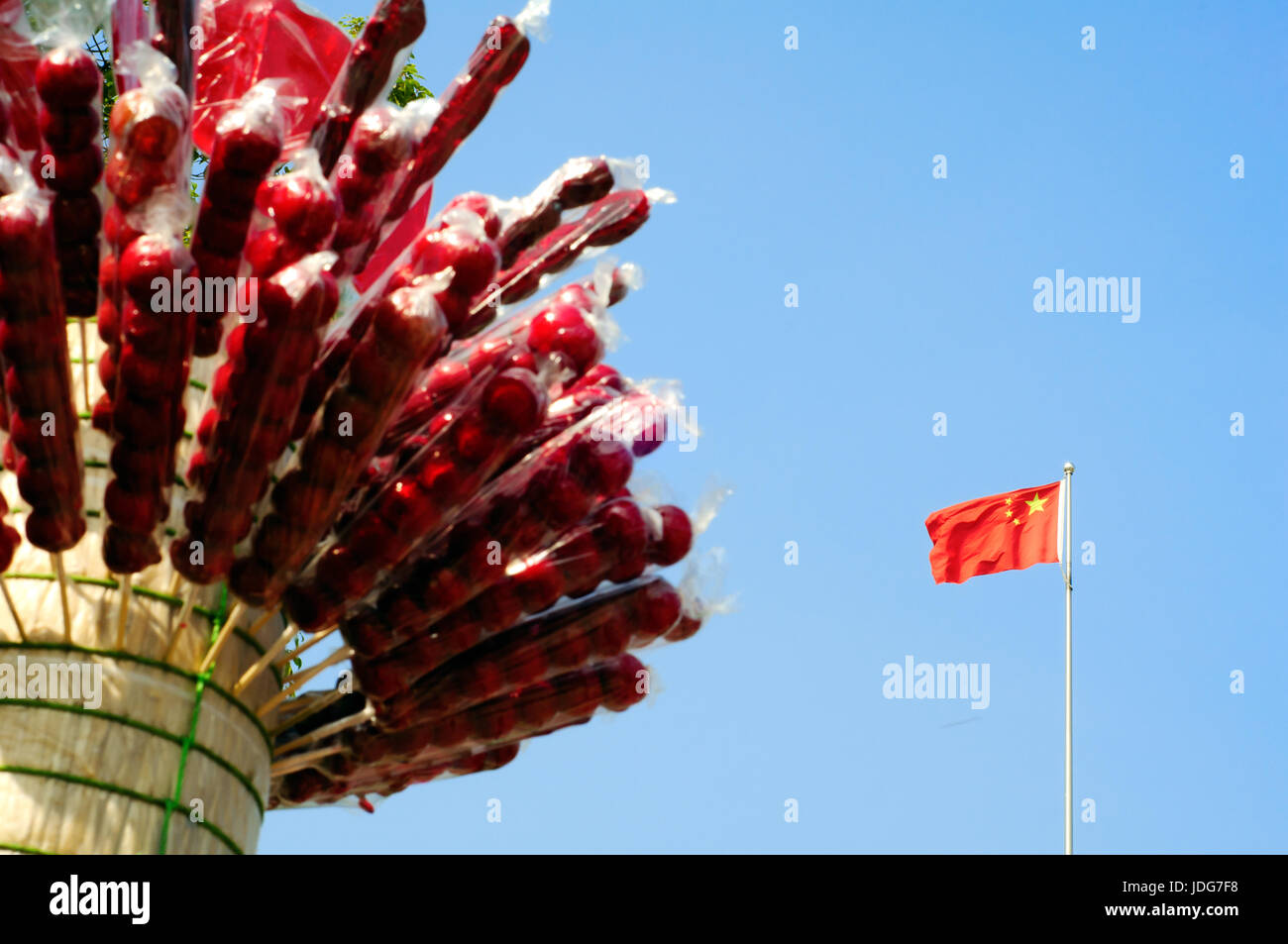 Bandiera nazionale cinese sotto la rivestite di zucchero haws. Rivestite di zucchero haws è Pechino iconici street food. Foto Stock
