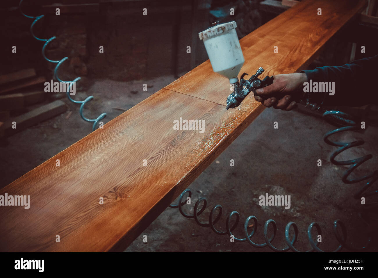 Il pittore in una fabbrica - Verniciatura industriale del legno con la pistola a spruzzo. soft focus. shallow dof. Foto Stock
