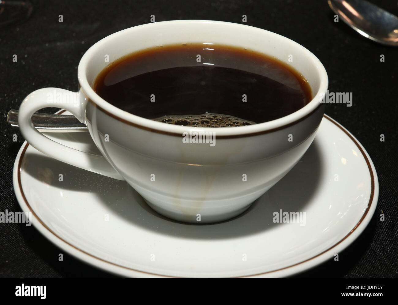 Nero caffè nella tazza e piattino sulla tovaglia nero Foto Stock