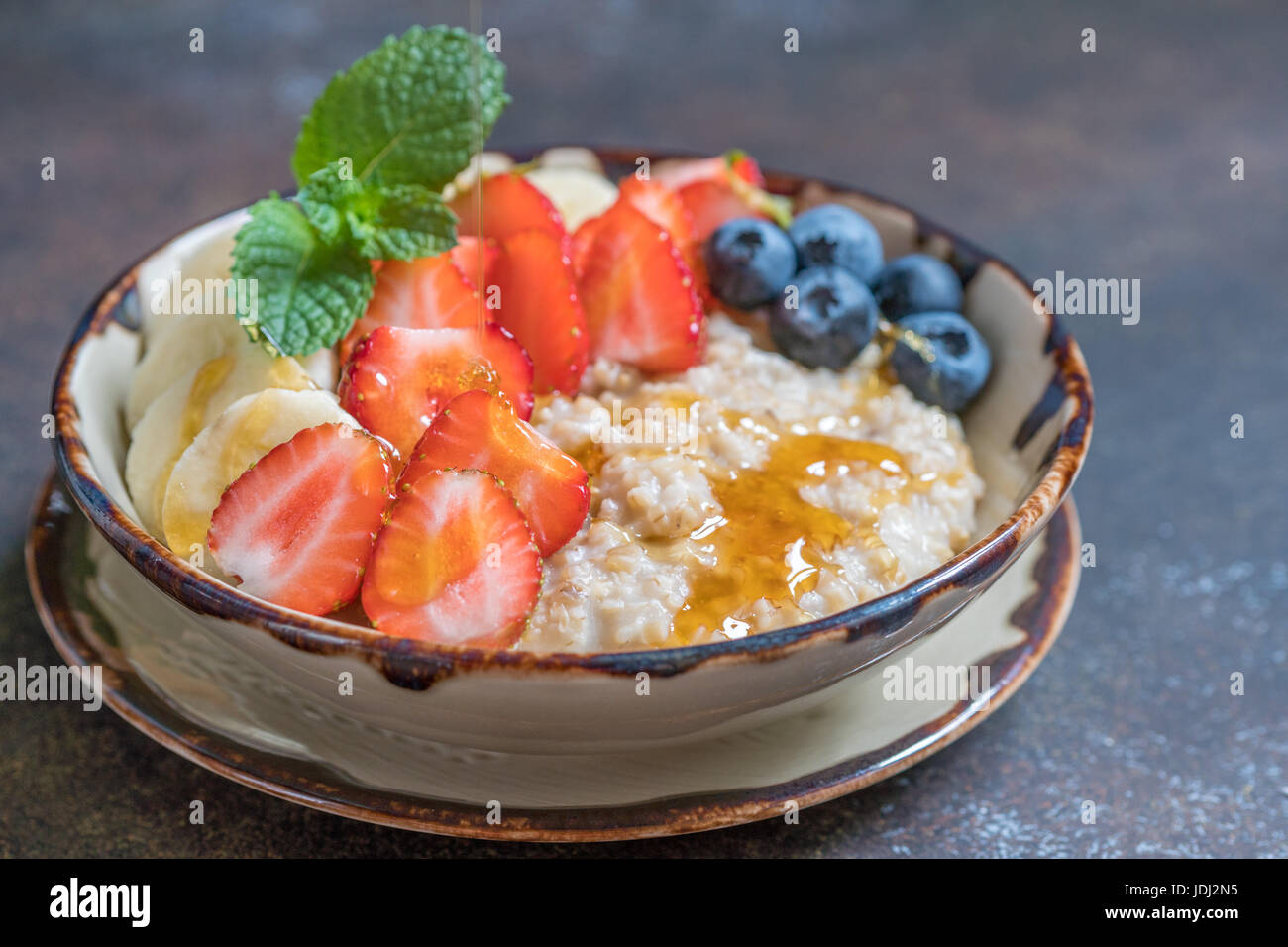 Ciotola di deliziose acciaio tagliati di avena con frutta fresca, miele Foto Stock