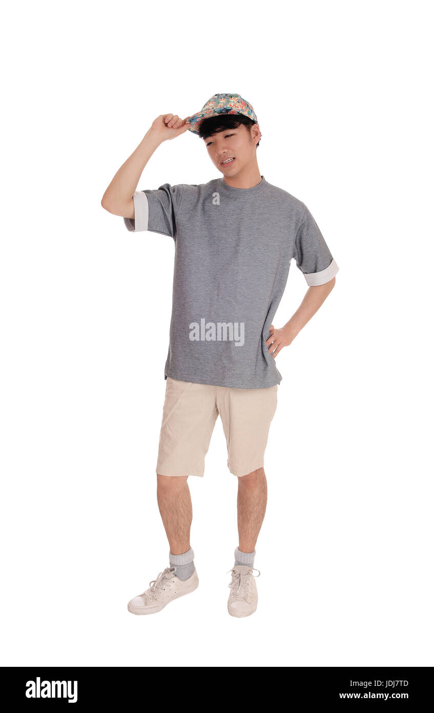 Un giovane adolescente asiatici in piedi in pantaloncini corti un grigio di una t-shirt con la sua mano sul suo cappuccio, isolato per sfondo bianco. Foto Stock