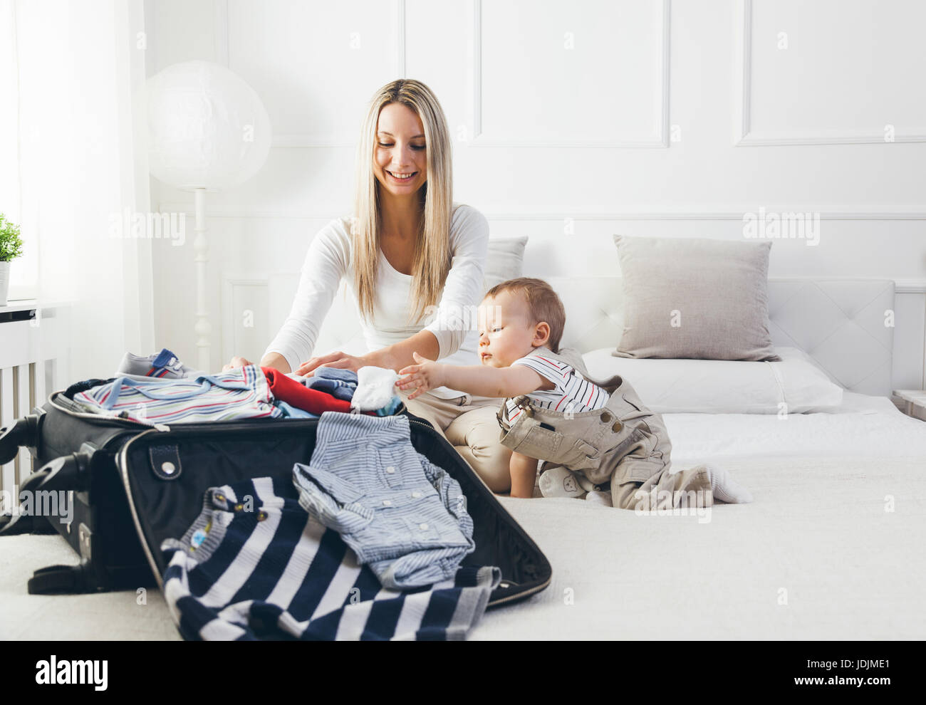 Viaggiare con i bambini. Felice madre con il suo bambino abiti di imballaggio per le proprie vacanze Foto Stock