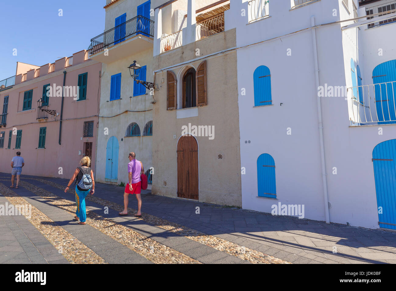 Alghero lungomare con vista del centro di età compresa tra i turisti passeggiano accanto gli edifici colorati di rivestimento del lungomare della città costiera di Alghero, in Sardegna. Foto Stock