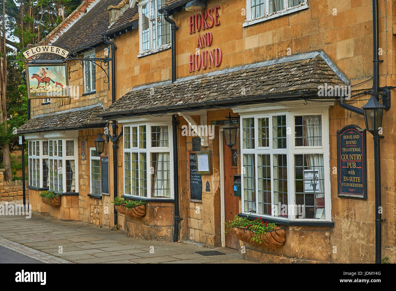 Cavallo e Hound public house nel Cotswold città di Broadway, con un vecchio pub pubblicità segno fiori Ales Foto Stock