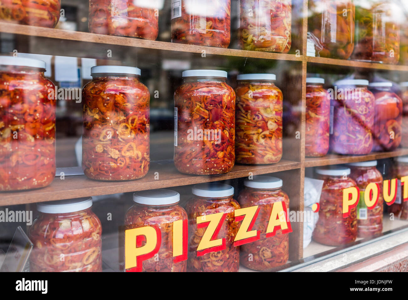 Marinata di peperoni rossi e gialli in grandi vasi sul display dietro il vetro della finestra con la pizza segno Foto Stock