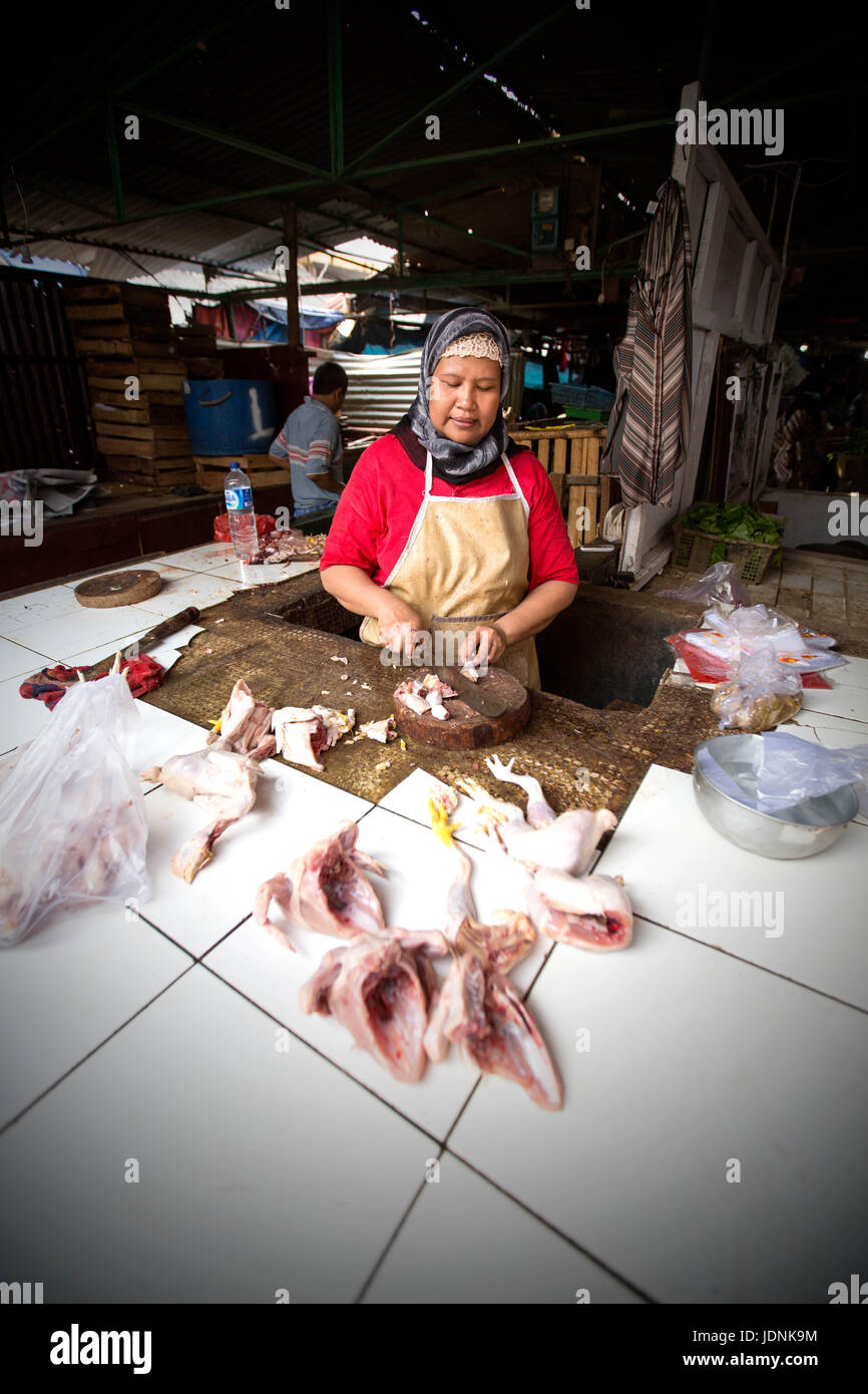 Donna musulmana la preparazione e vendita di pollo in Indonesia Foto Stock