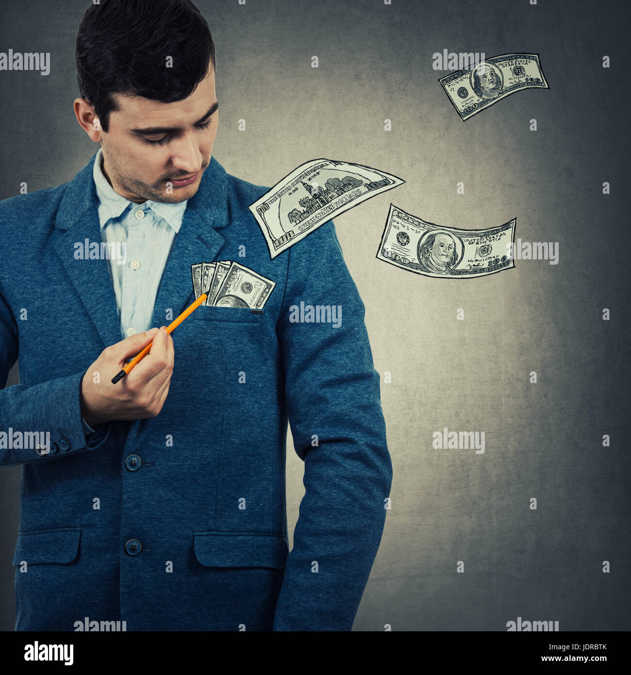 Imprenditore puntando una matita per il suo pocket, cercando di attirare imaginetive denaro. Simbolo di corruzione, isolato sul muro grigio Sfondo. Foto Stock