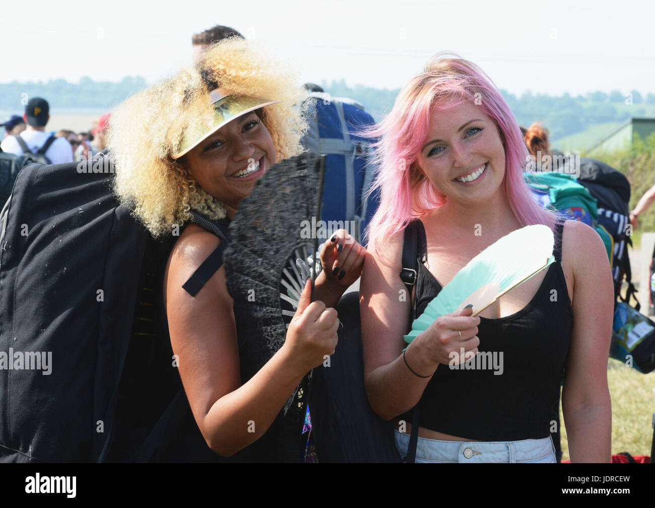 Reamma Edwards (sinistra) e Beth verde, entrambi da Bristol, ventola stessi per mantenere fresco in coda come essi arrivano per il festival di Glastonbury presso l'azienda agricola degna in Pilton, Somerset. Foto Stock