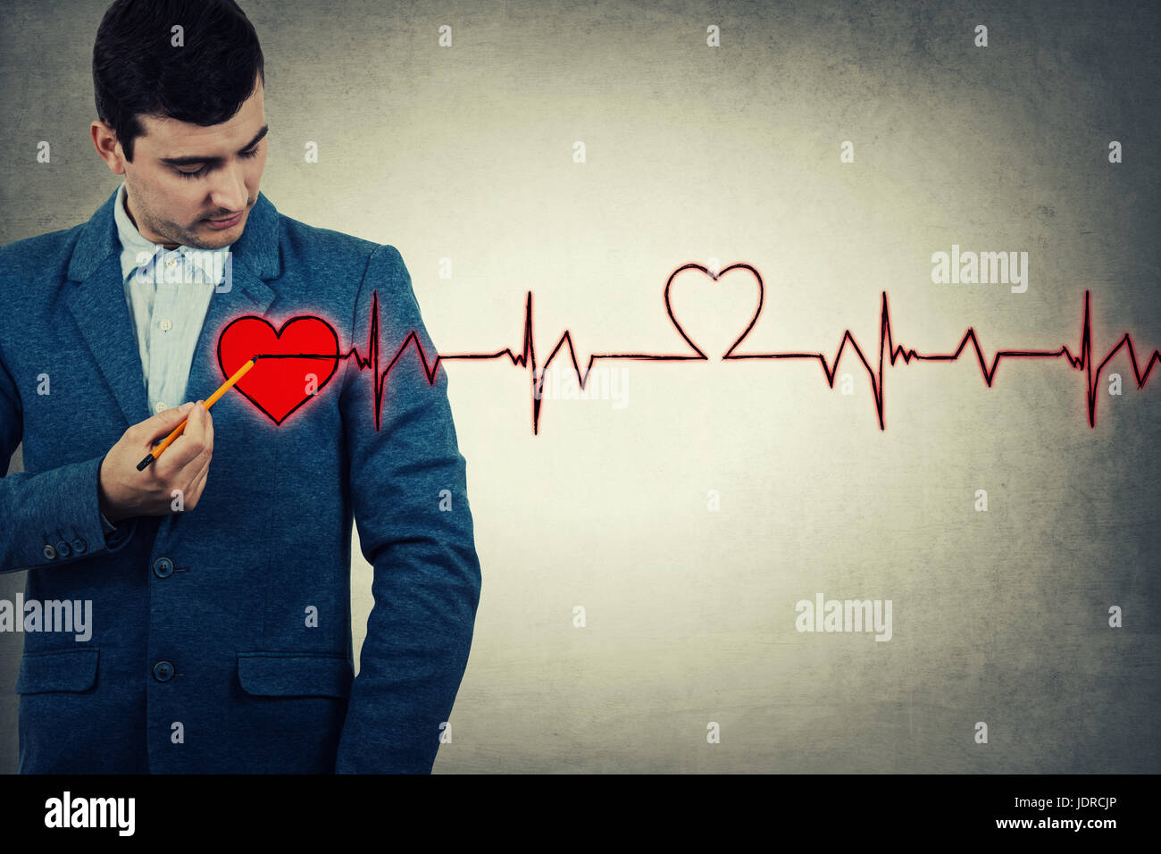 Giovane imprenditore puntando una matita per il suo petto, cercando di attirare imaginetive cuore rosso e il battito cardiaco cardiogram. La carità, health care, una donazione Foto Stock