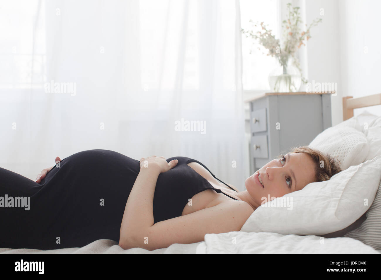 Trasognata incinta donna giaceva a letto Foto Stock