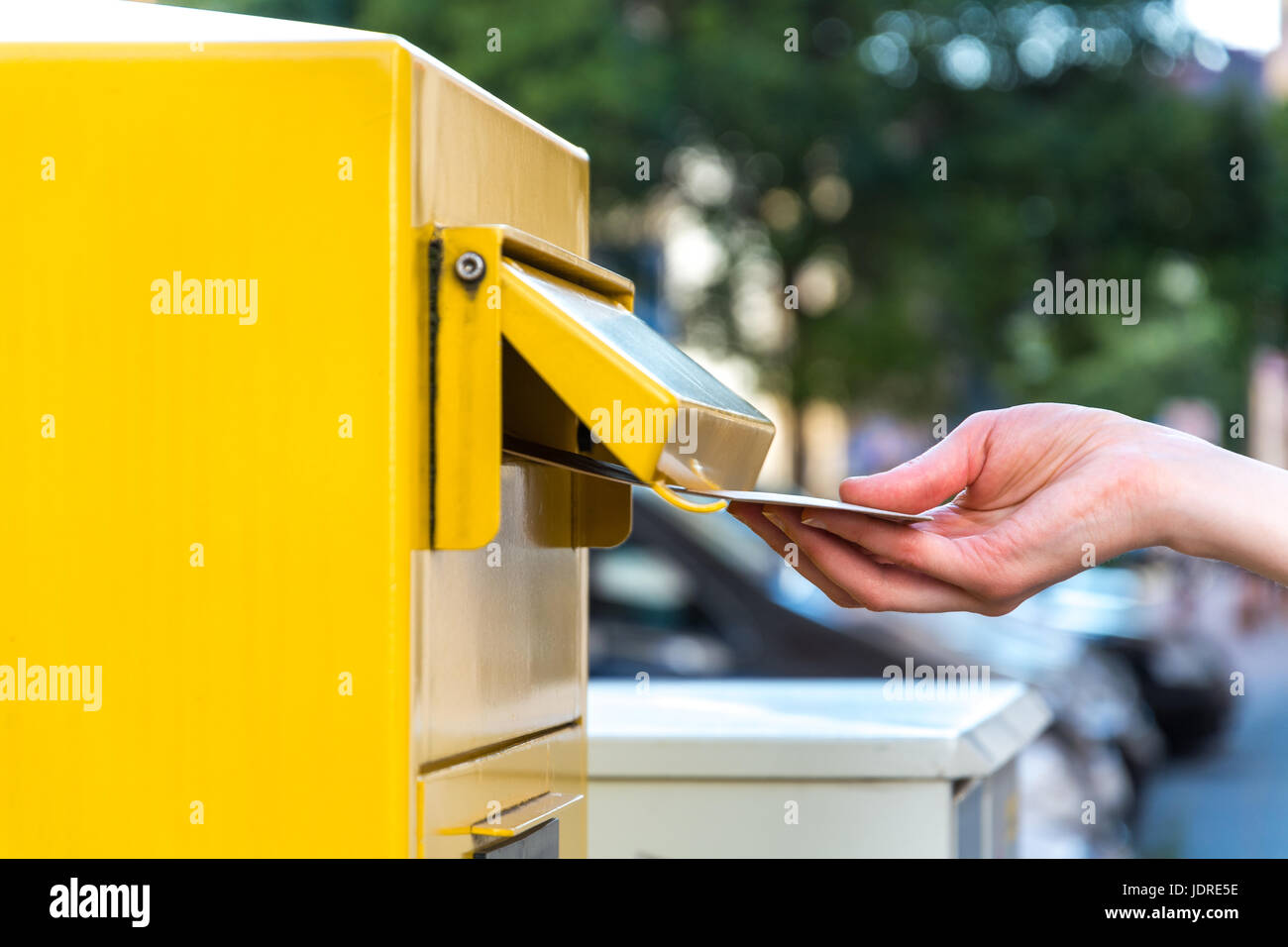 Gettando una lettera in tedesco mailbox giallo Foto Stock