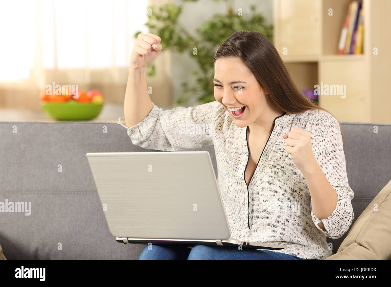 Unico Excited donna controllo news in un laptop seduto su un divano ... Unico Excited donna controllo news in un laptop seduto su un divano ...