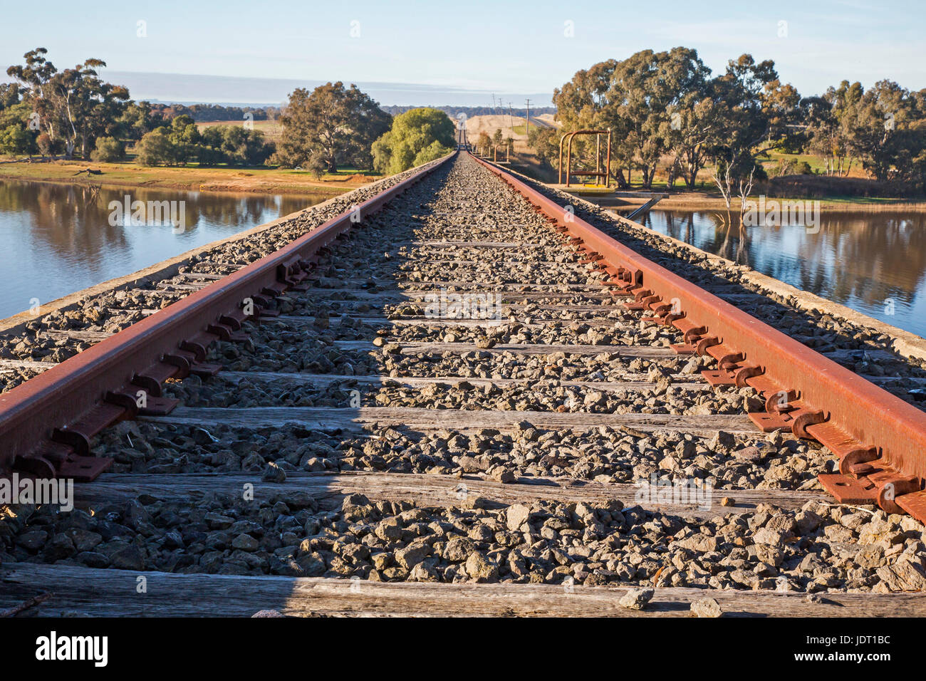 Le linee ferroviarie per l'orizzonte alla ferroviarie dismesse ponte sul torrente Joyces alla sua entrata al lago di Cairn Curran. La Newstead, Victoria, Australia Foto Stock