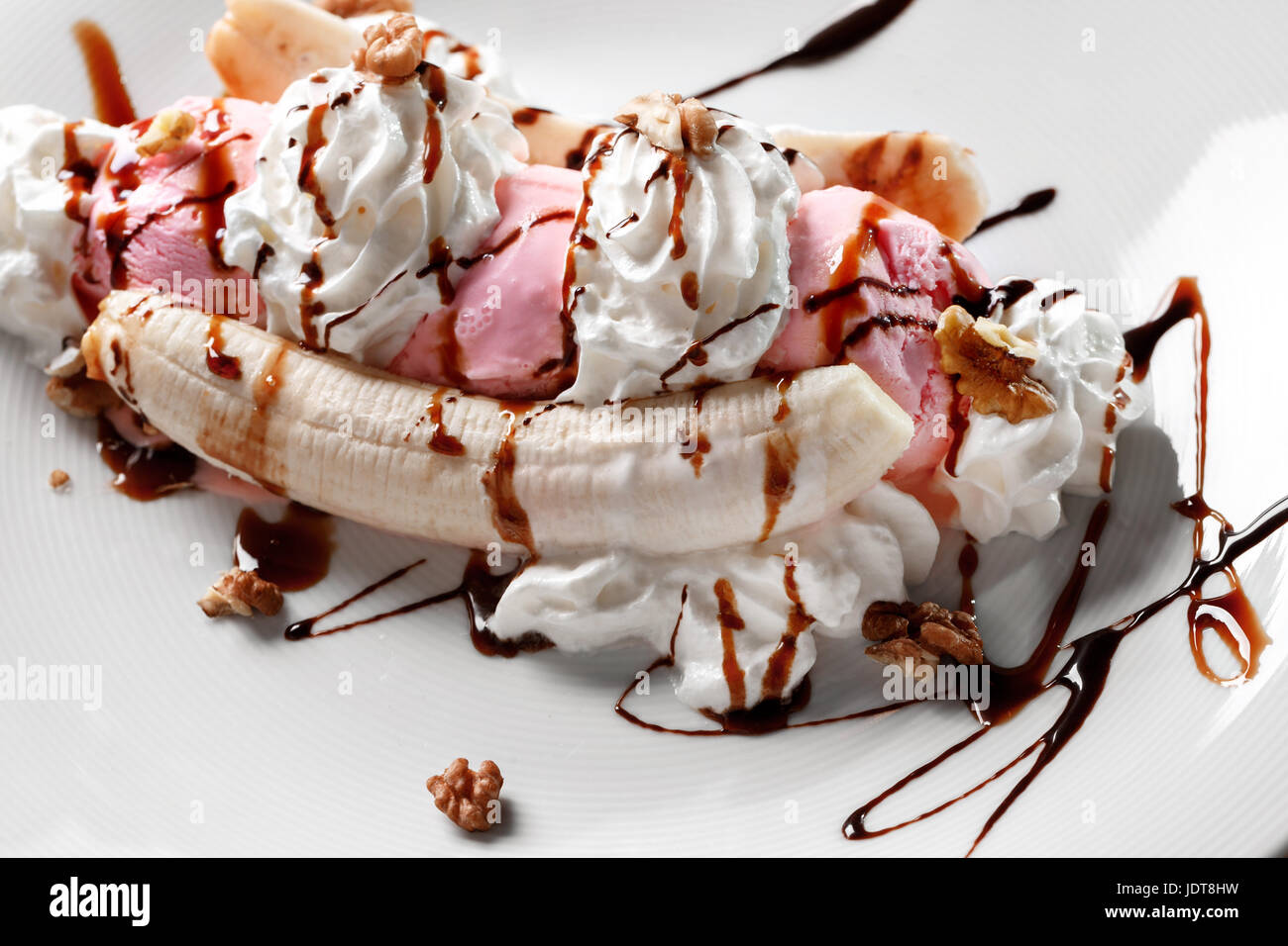 Tropical banana split con cioccolato pioggerella su tre palline di Cioccolato, fragola e gelato alla vaniglia sulle banane fresche Foto Stock