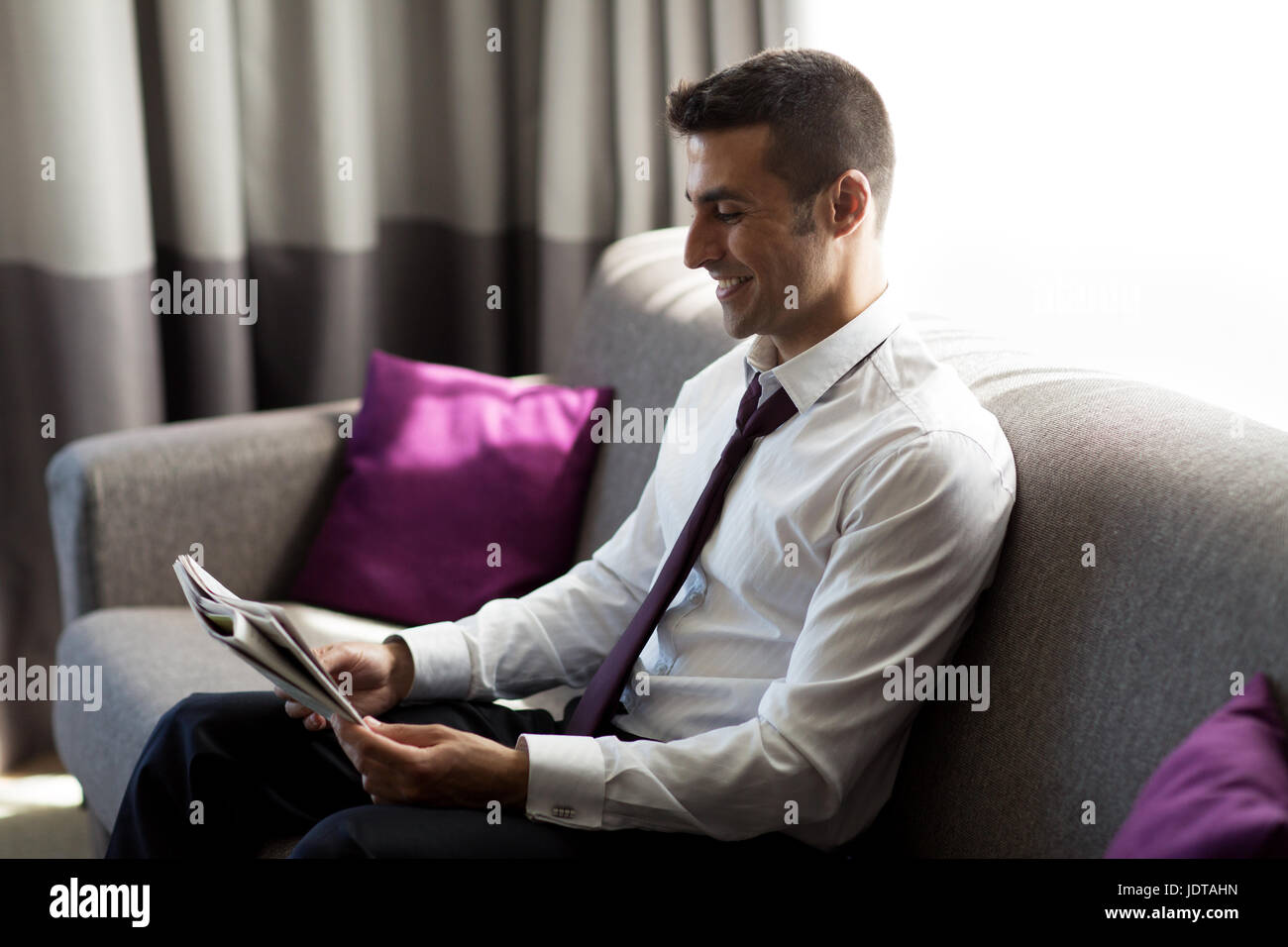 Happy businessman leggendo il giornale in camera di albergo Foto Stock