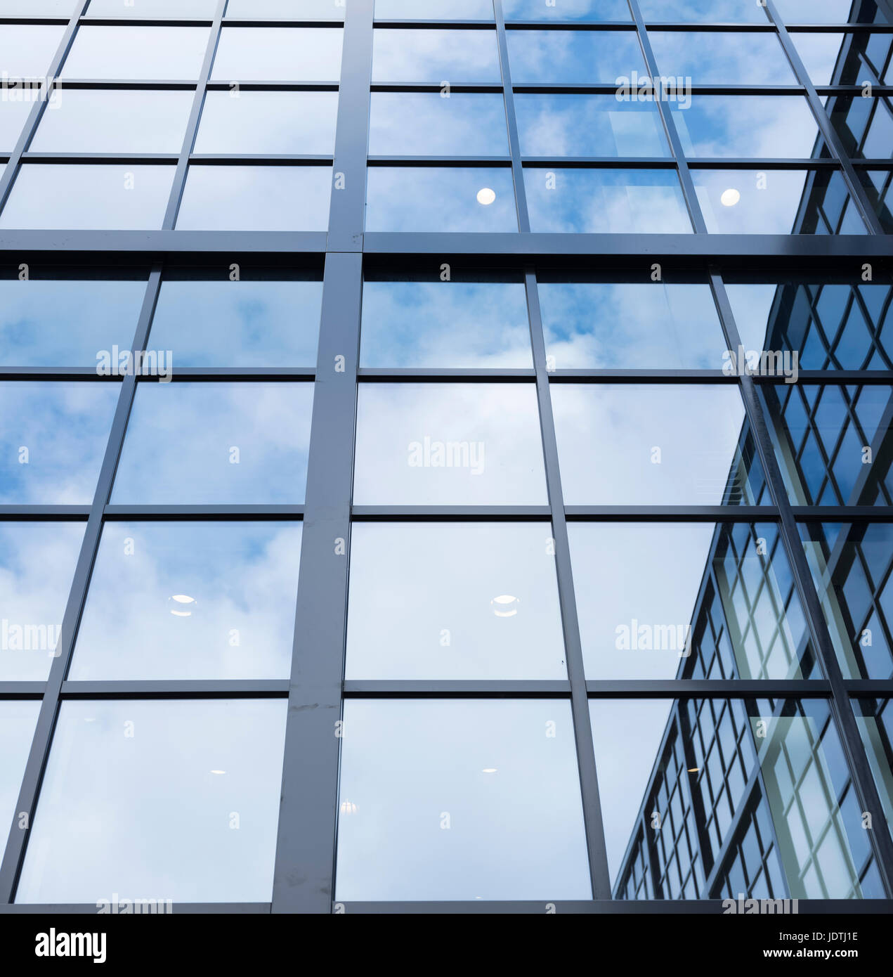 Riflessi di cielo blu con nuvole e altro edificio in facciata di vetro del moderno edificio per uffici Foto Stock