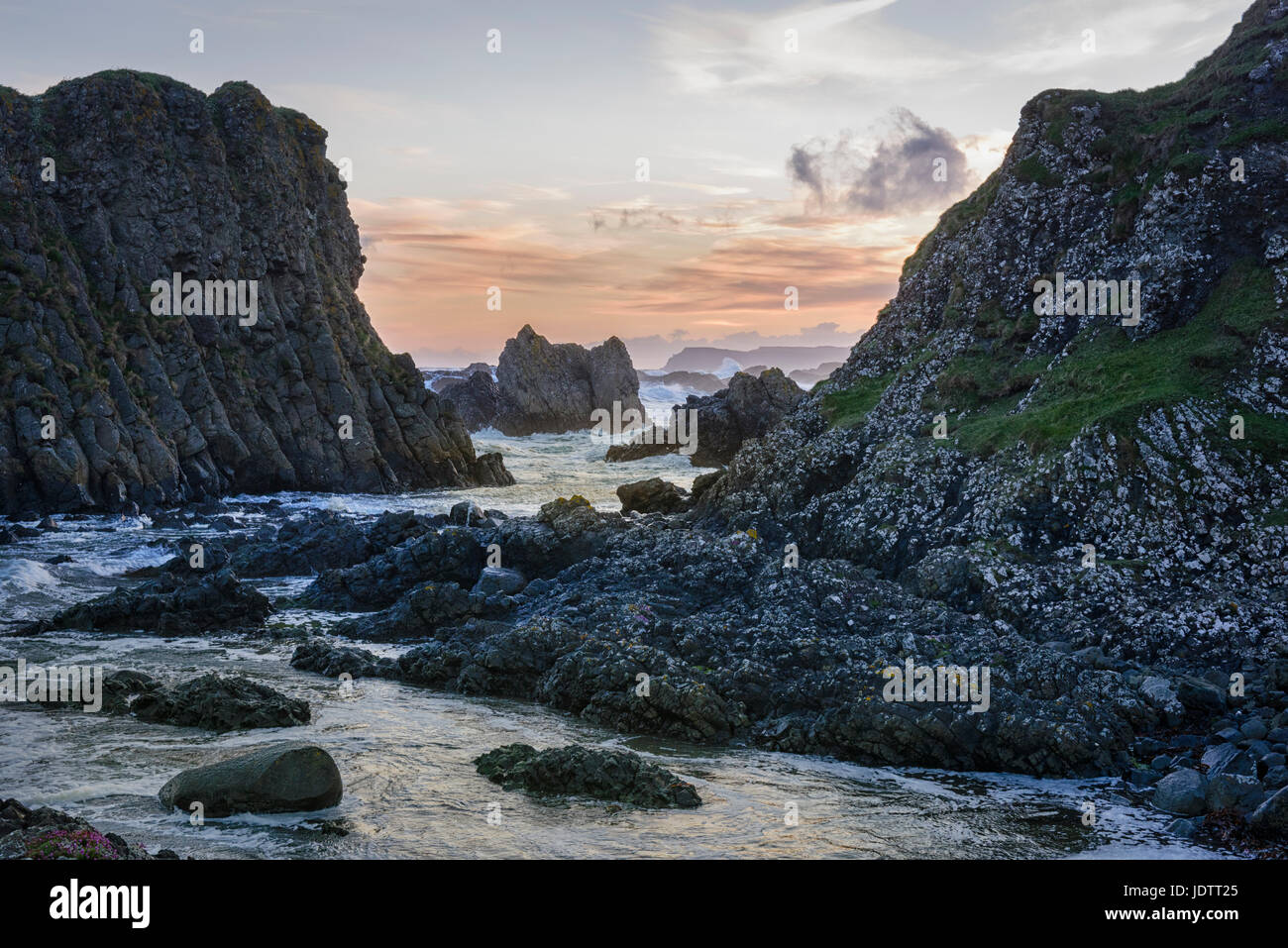 Costa rocciosa scogliere e le isole e il mare pile sulla contea di Antrim coast in Irlanda del Nord al crepuscolo Foto Stock