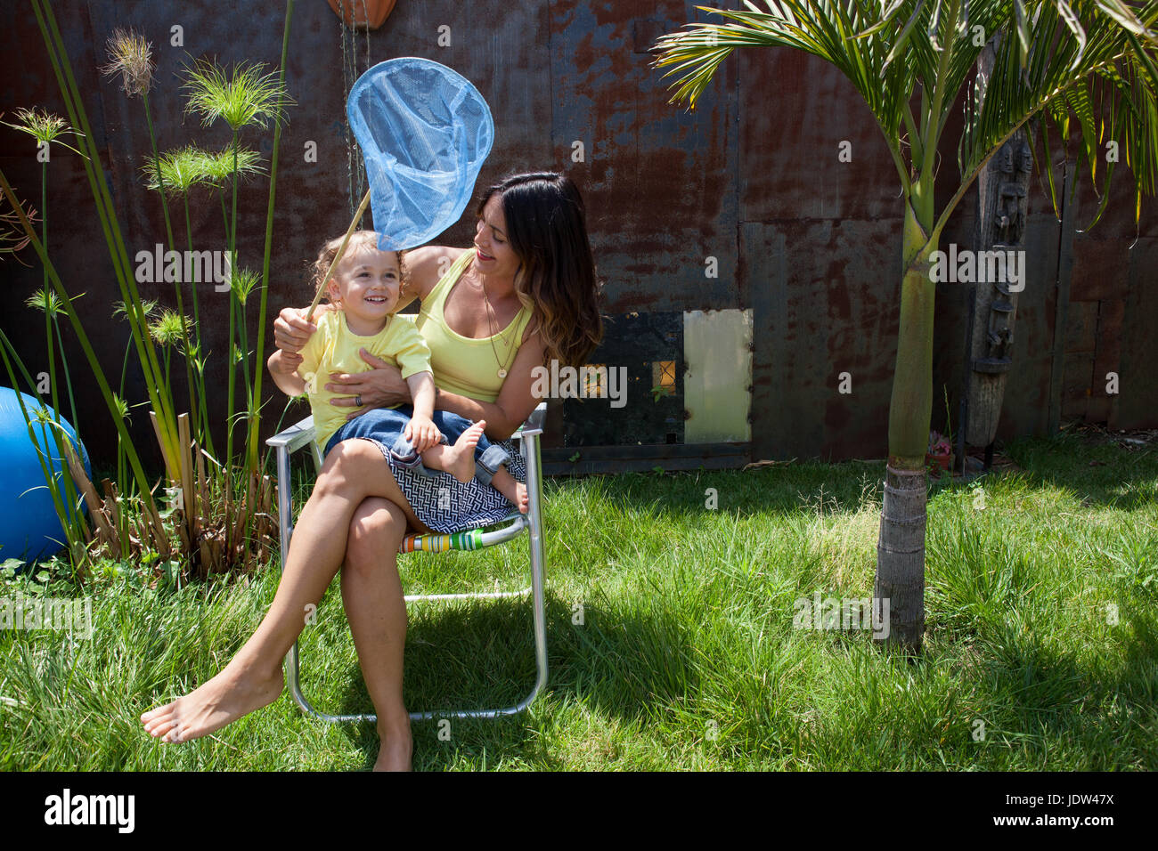 Madre e figlio seduti su una sedia in giardino con rete da pesca Foto Stock