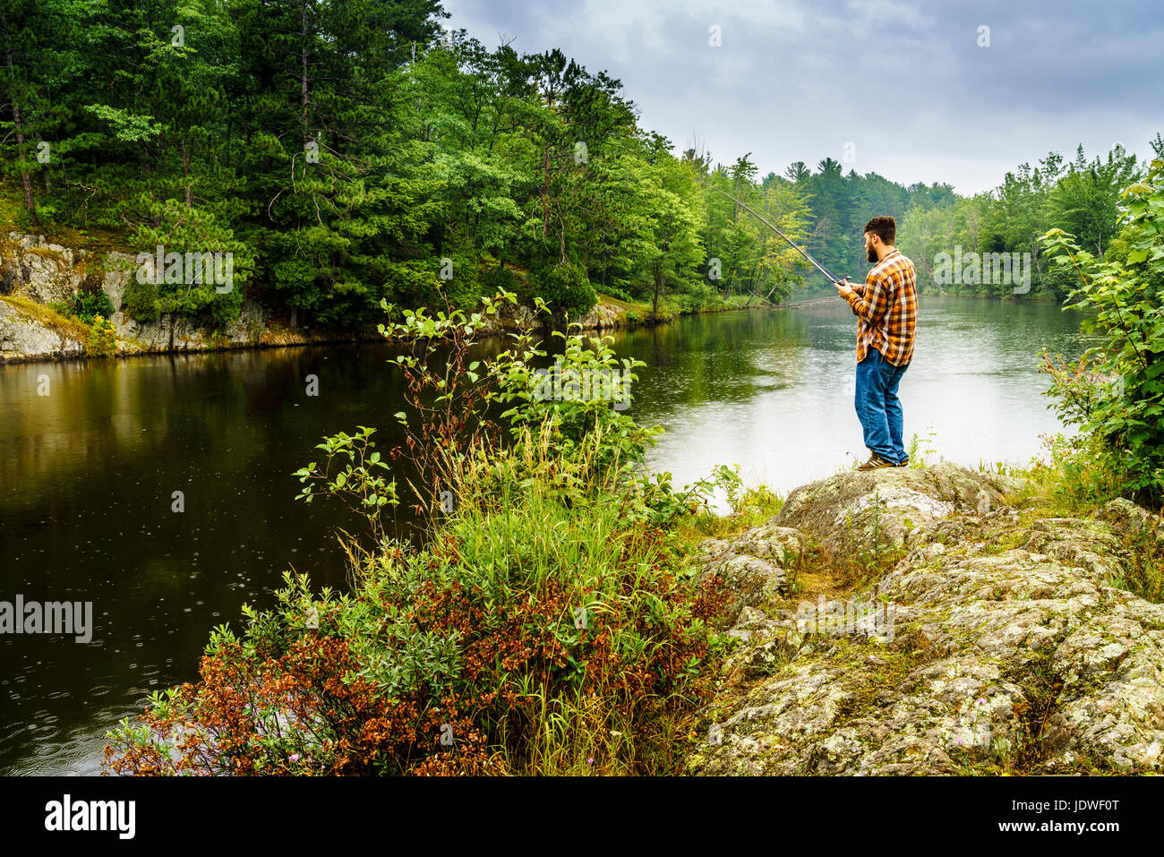 Penisola Superiore, Michigan, Agosto 11, 2016: un pescatore dedicato è la pesca in un fiume vicino a Marquette, Michigan Foto Stock