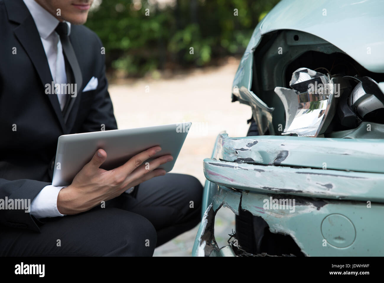 Vista laterale della scrittura sulla clipboard mentre agente di assicurazione auto esame dopo un incidente Foto Stock