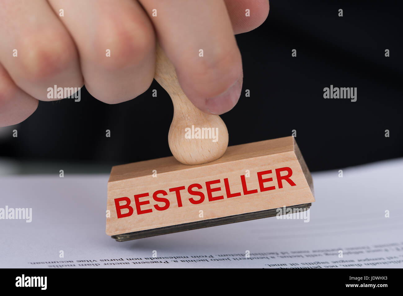 Primo piano della mano del documento di stampaggio con il best-seller timbro di gomma a tavola in office Foto Stock