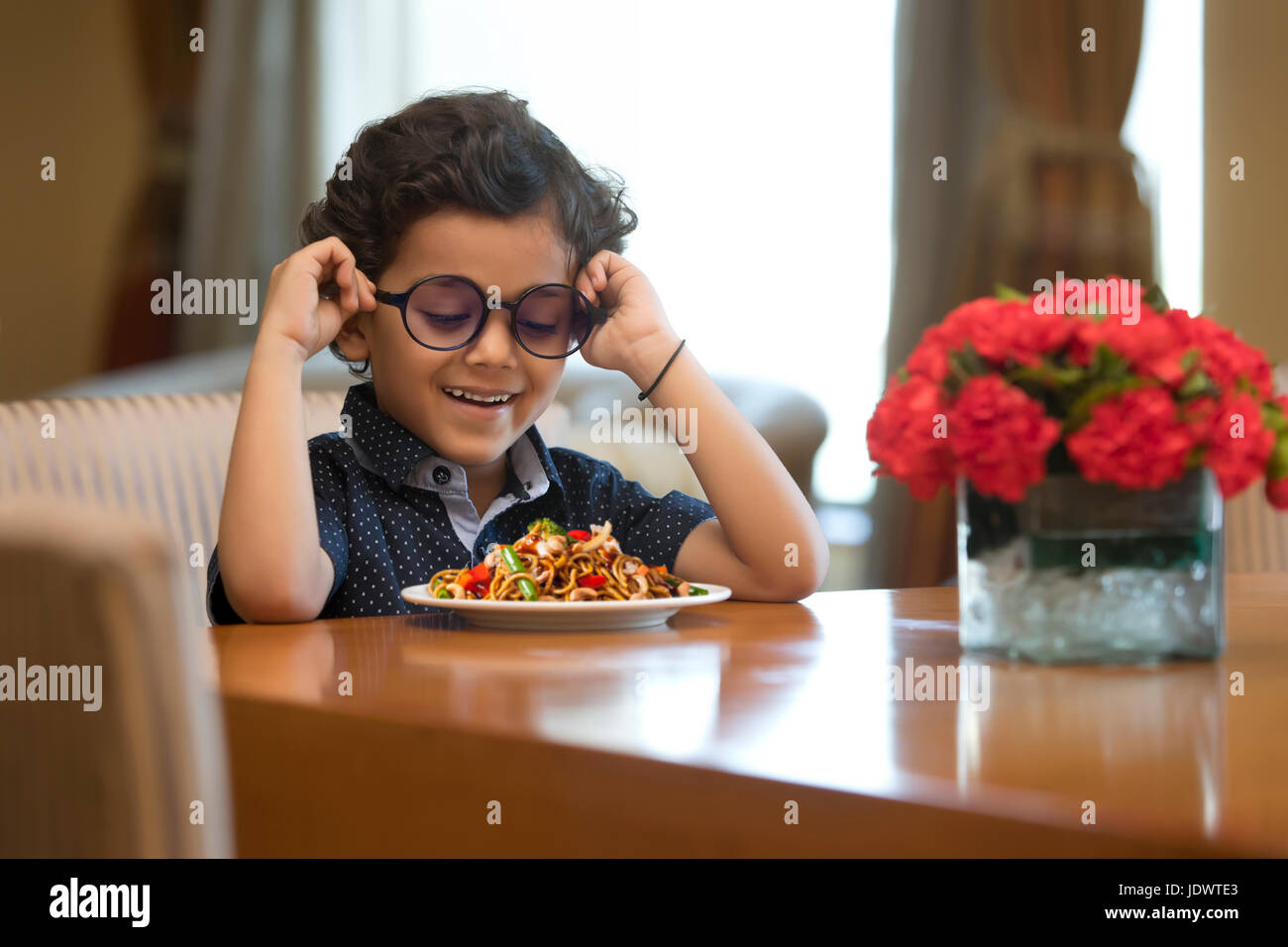 Primo piano del ragazzo sorridente con piastra di tagliatelle sul tavolo Foto Stock