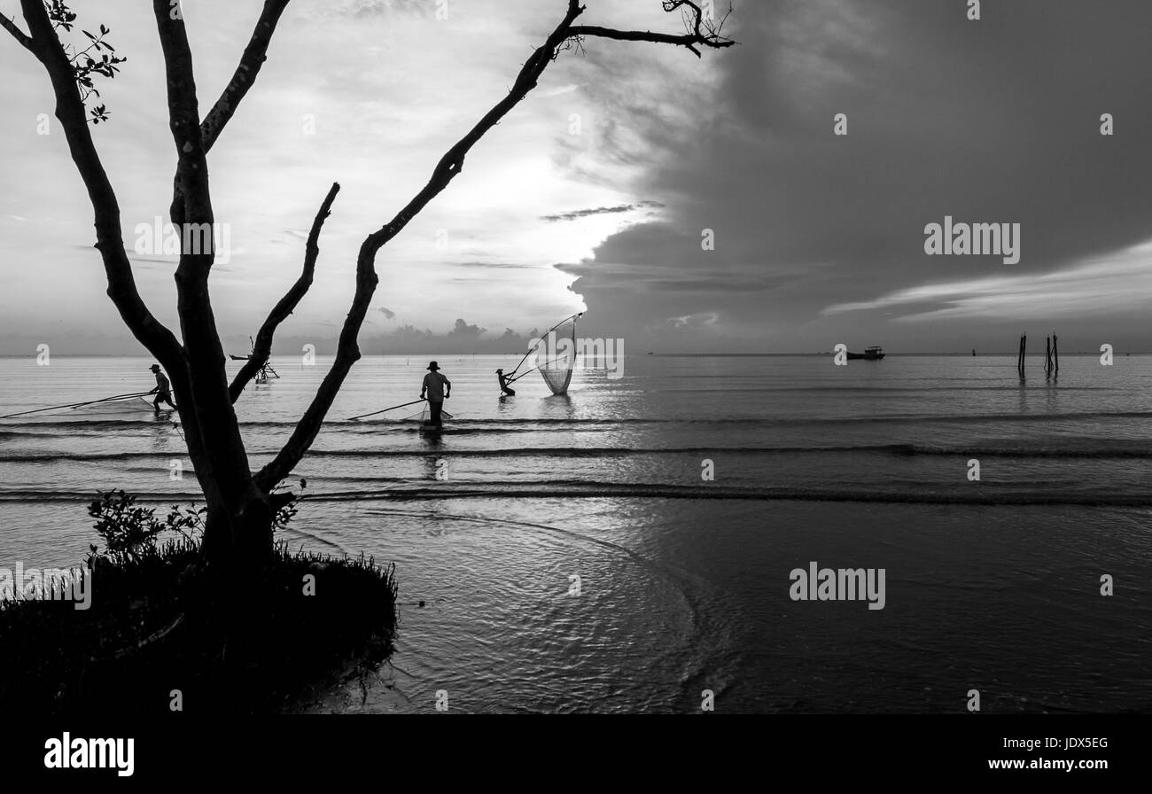 Mare di scavo clam sunrise pescatore rete da pesca Tan Thanh beach Go Cong Tien Giang Viet Nam in bianco e nero Foto Stock