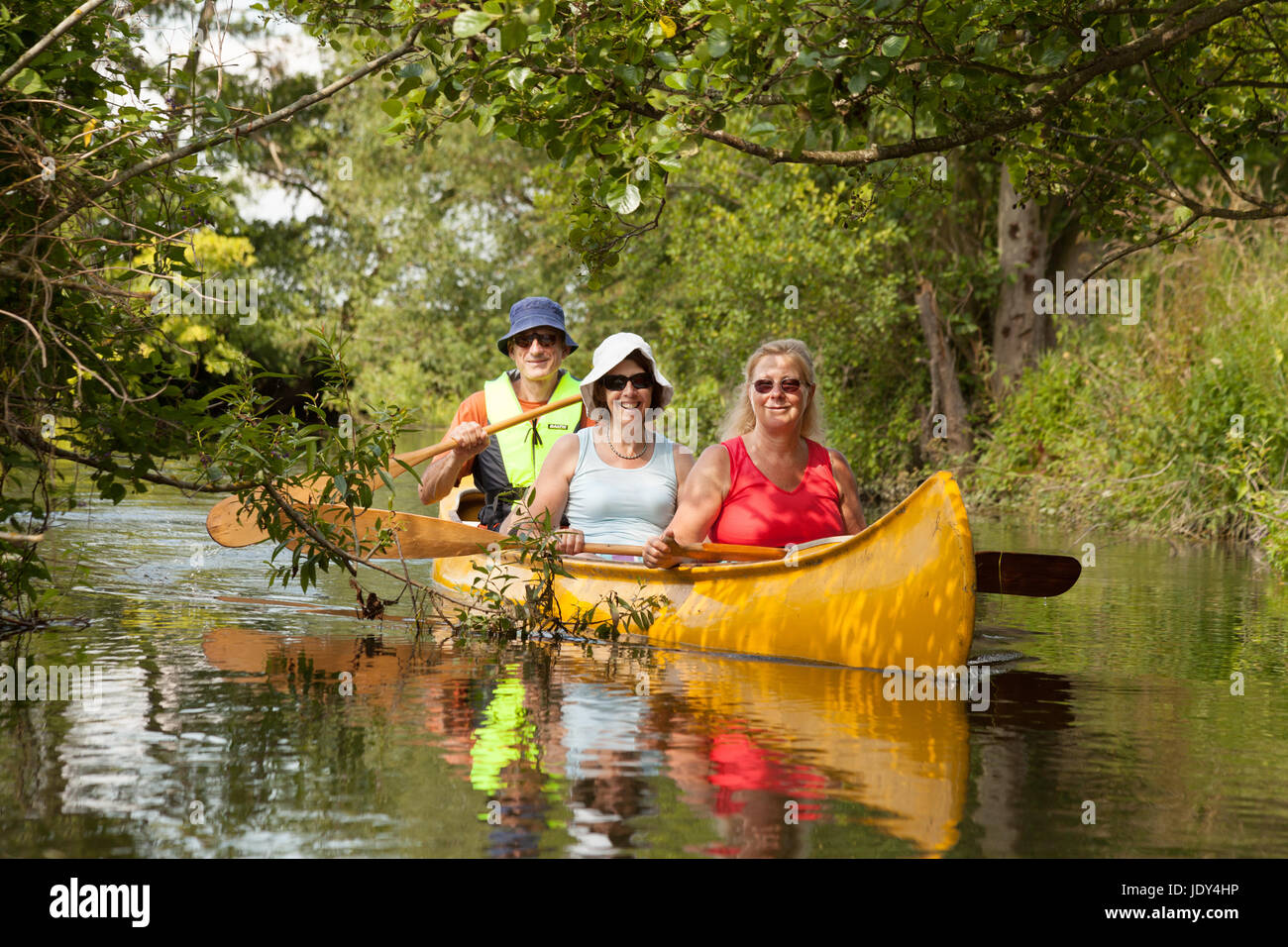 Tre persone a bordo di una canoa e canottaggio sul fiume Lodden, Oxfordshire England Regno Unito Foto Stock