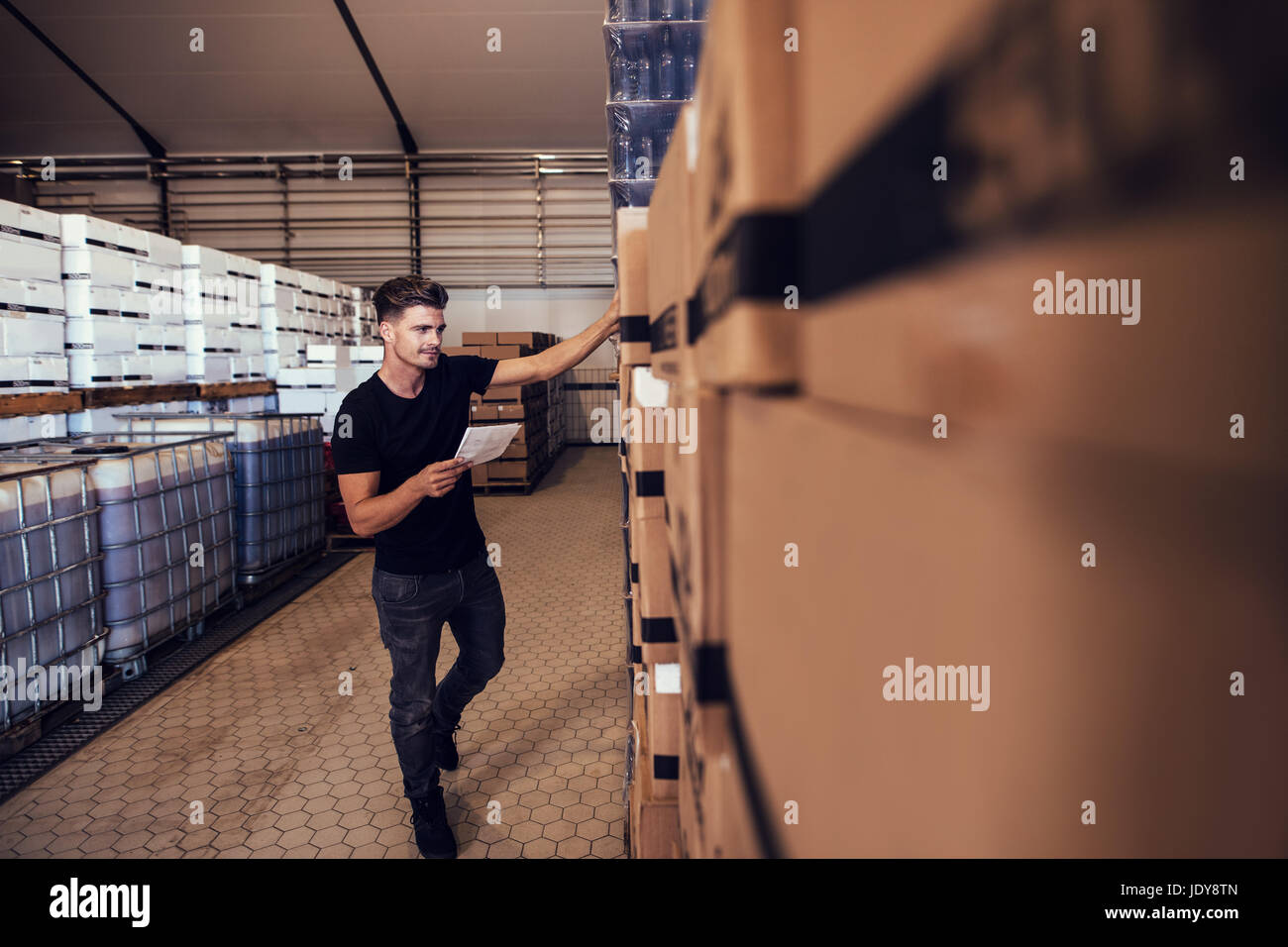 Giovane uomo prendendo le scorte di birra confezionata in box in magazzino. Responsabile di magazzino tenendo l'inventario dei prodotti finiti presso la fabbrica di birra. Foto Stock