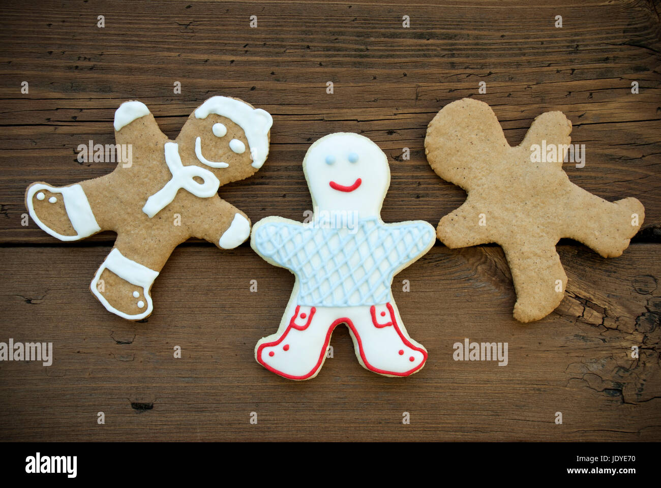 Tre felice guardando lo zenzero pane uomo, diversi i cookie con decorazione o vuoto, sullo sfondo di legno Foto Stock