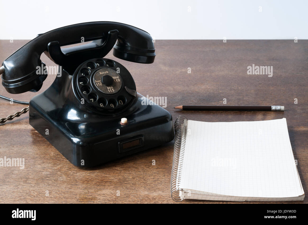Altes Telefon mit Schreibblock fuer Textfreiraum und Bleistift auf einem Schreibtisch. Foto Stock