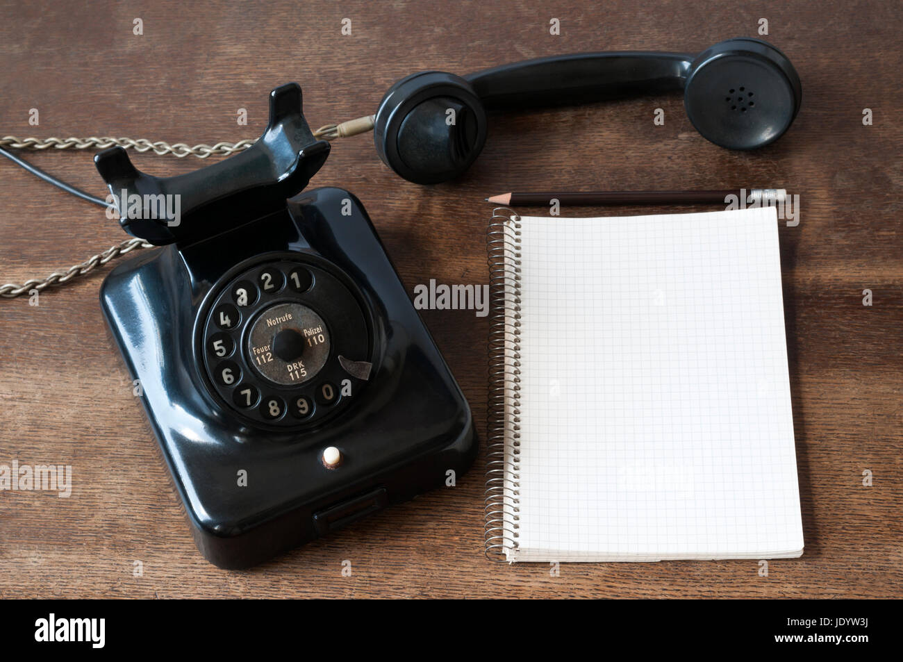 Altes Telefon mit Schreibblock fuer Textfreiraum und Bleistift auf einem Schreibtisch. Foto Stock