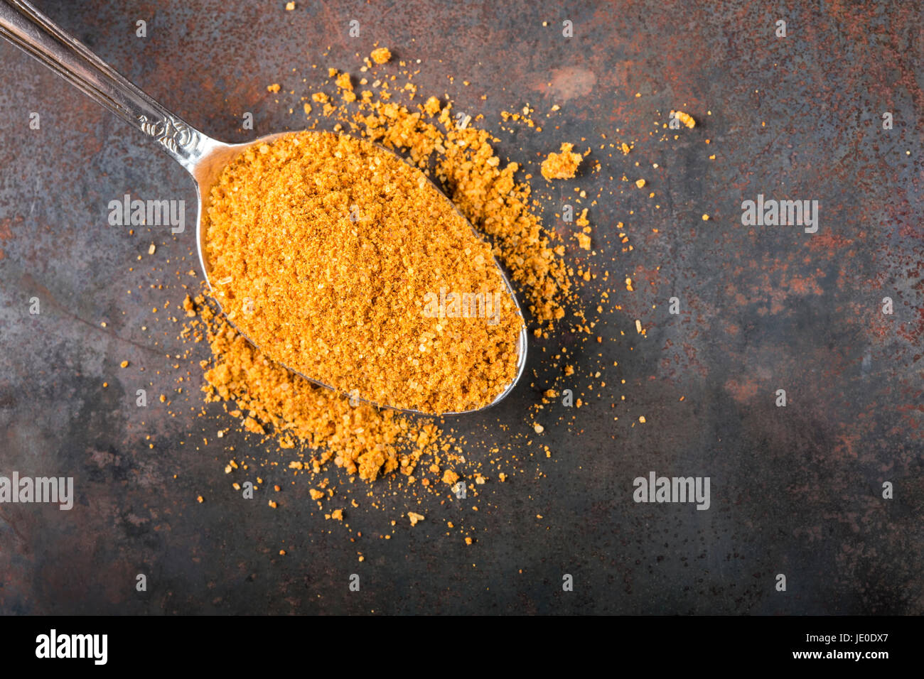 Cucchiaio riempito con le spezie per la preparazione di arrosti su sfondo arrugginito con spazio di copia Foto Stock