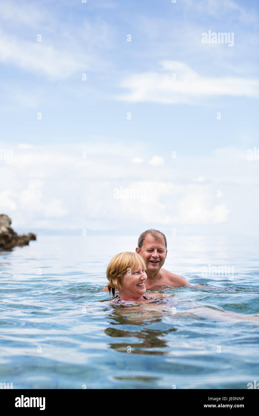Coppia senior godendo la pensione su un seacost, avente una nuotata nel mare, ridendo togther, rimanendo attivo e positivo Foto Stock