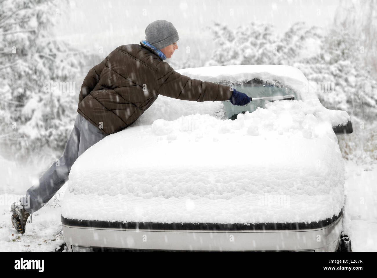 Junger Mann entfernt den Schnee von seinem Fahrzeug Foto Stock