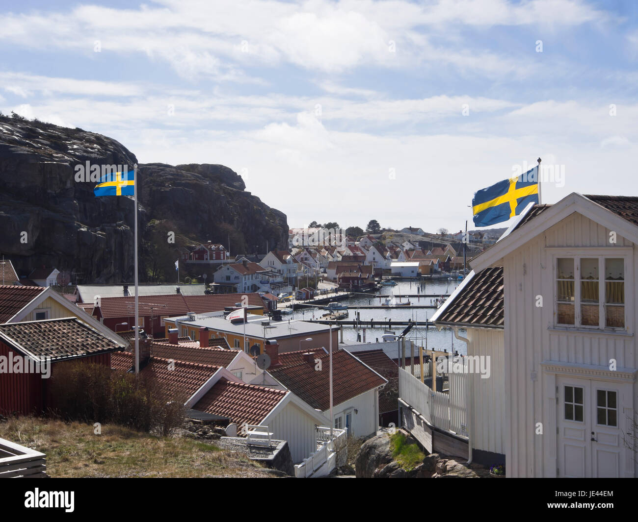La piccola città di Fjallbacka sulla costa occidentale della Svezia, una destinazione di vacanza, vista del porto e marina, bandiera svedese sventola sui tetti Foto Stock