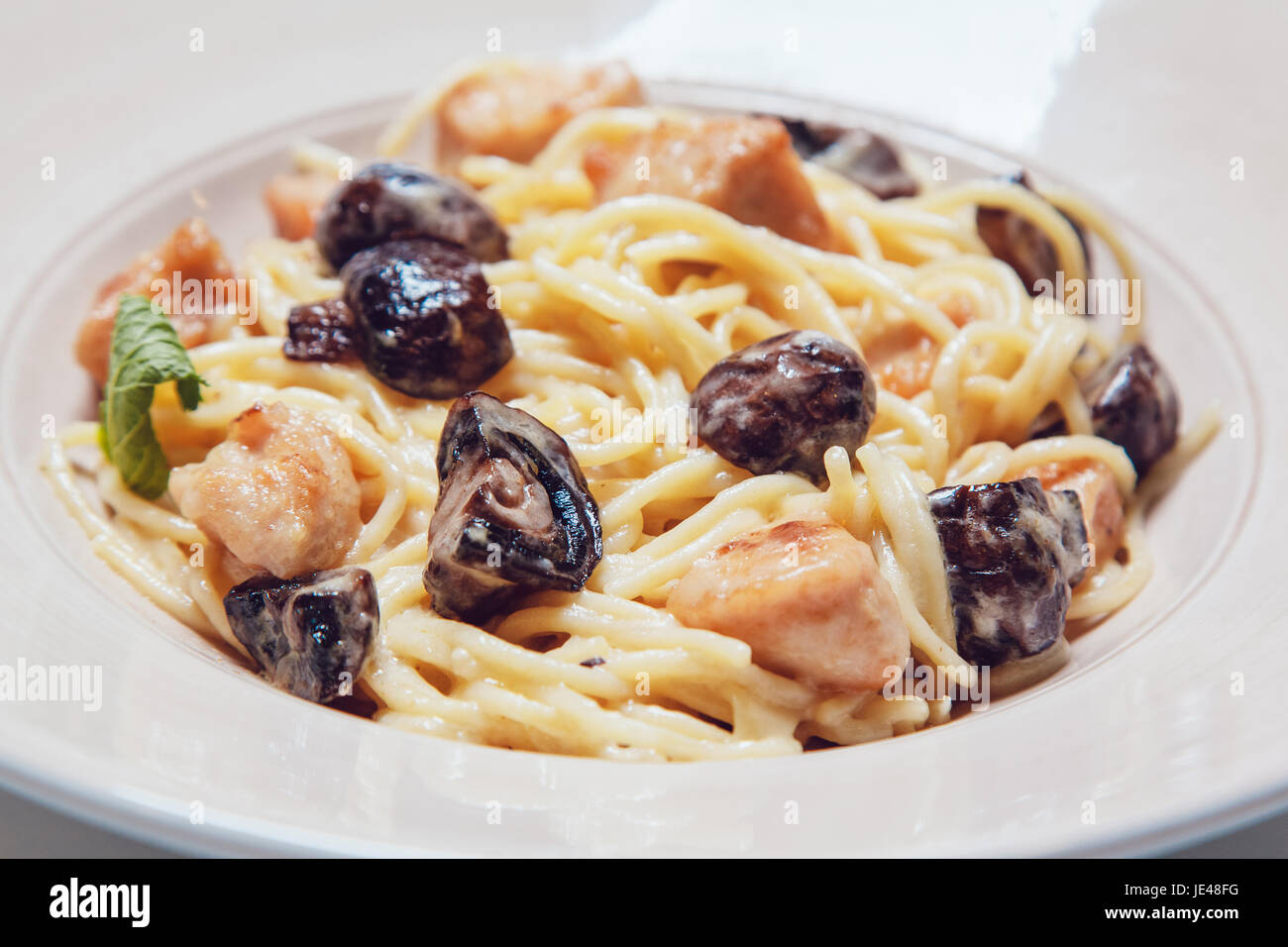 Spaghetti con pollo e champignon in salsa cremosa. Foto Stock