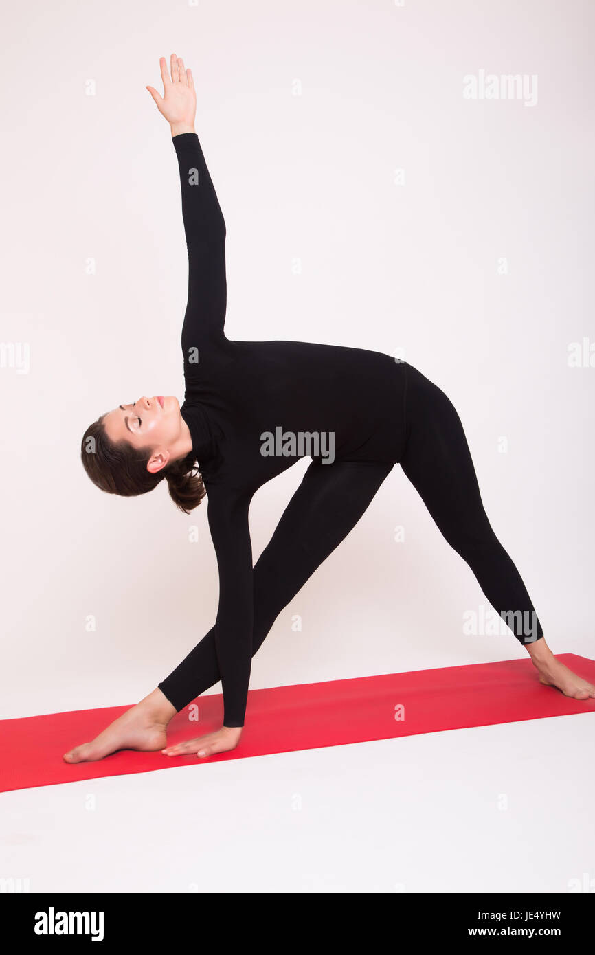 Bella ragazza atletica in abito nero fare Yoga asana. Isolato su sfondo bianco. Foto Stock