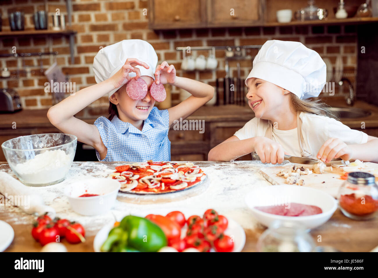 Kids in chef cappelli divertirsi mentre si effettua la pizza Foto Stock