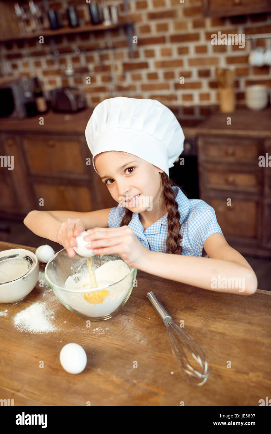 Bambina con chef hat rendendo la pasta per i cookie Foto Stock