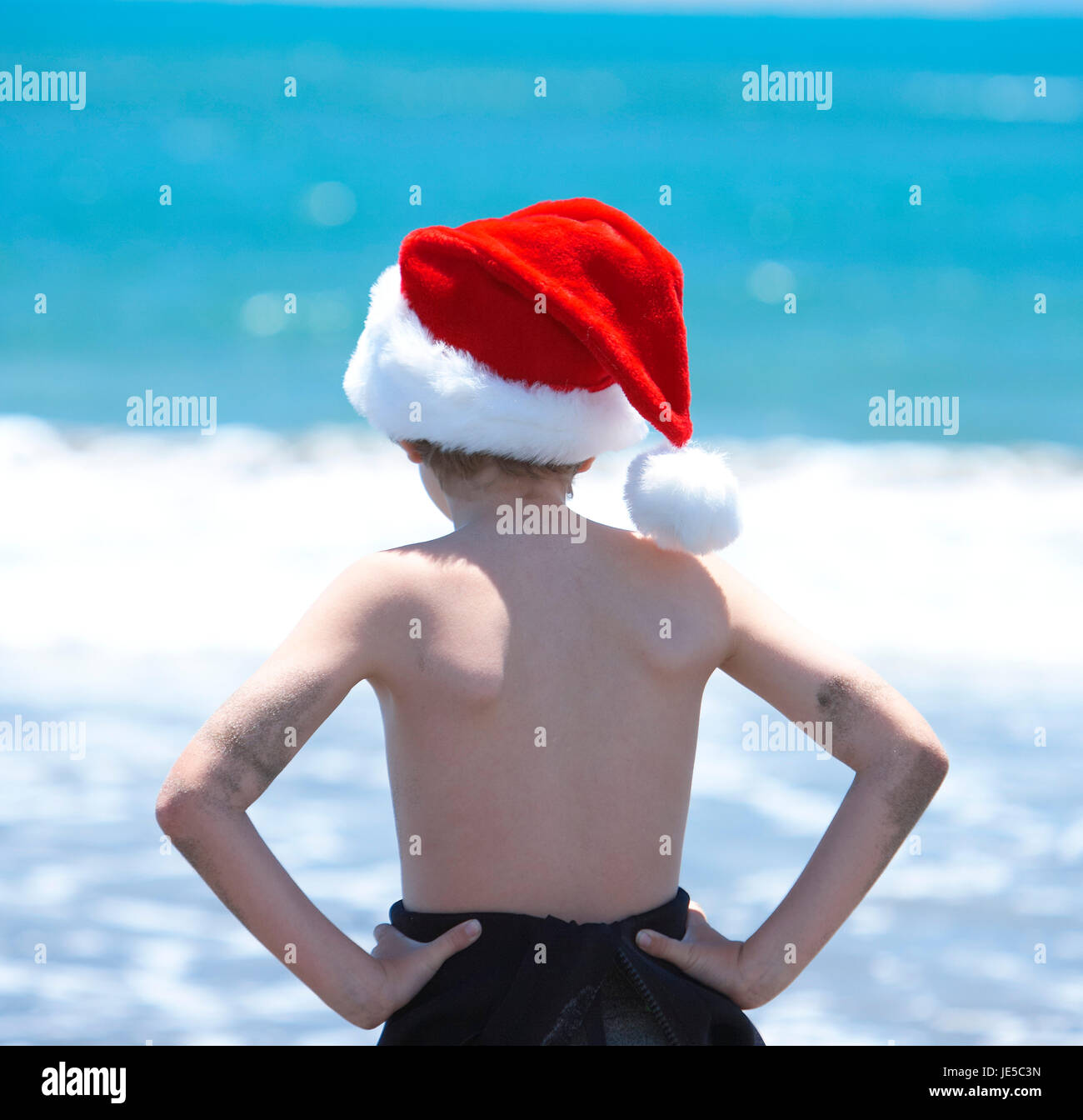 Ragazzo(9) vestita in rosso bianco santa hat sulla spiaggia in estate Foto Stock