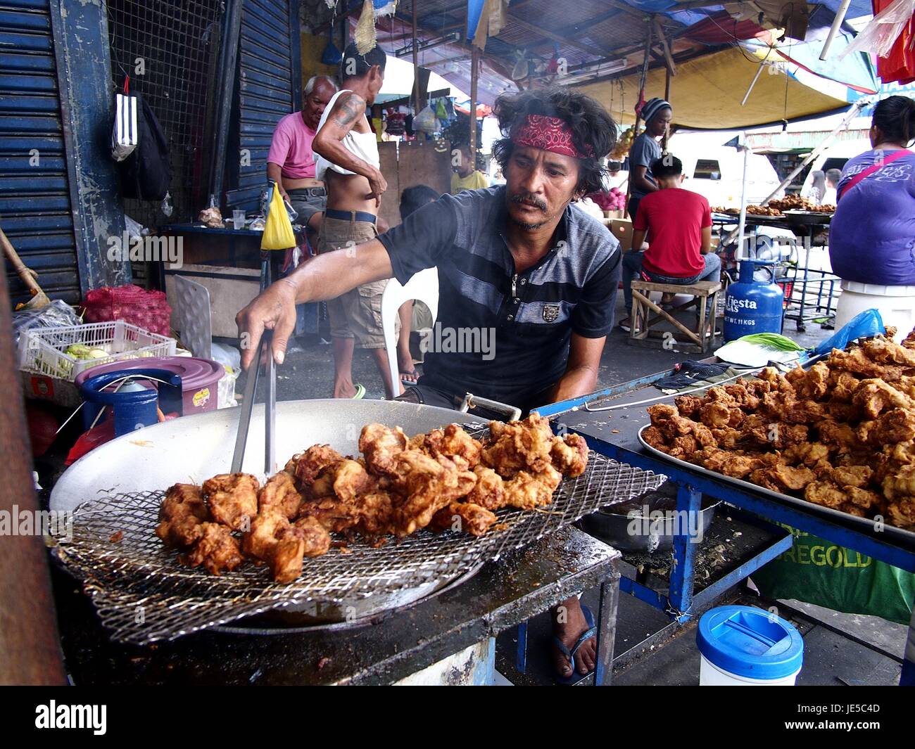 ANTIPOLO City, Filippine - 14 giugno 2017: un cibo di strada cuochi del fornitore il pollo fritto presso il suo negozio di fortuna. Foto Stock